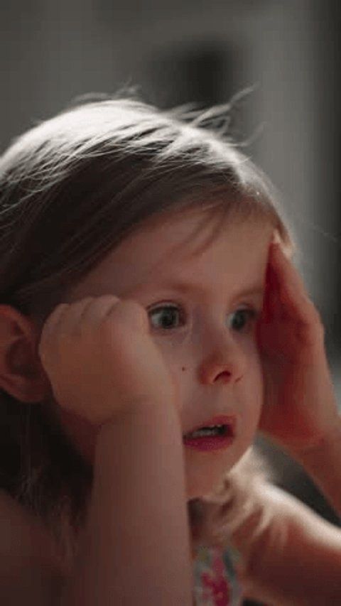 Kind schaut mit großen Augen aufmerksam auf einen Bildschirm