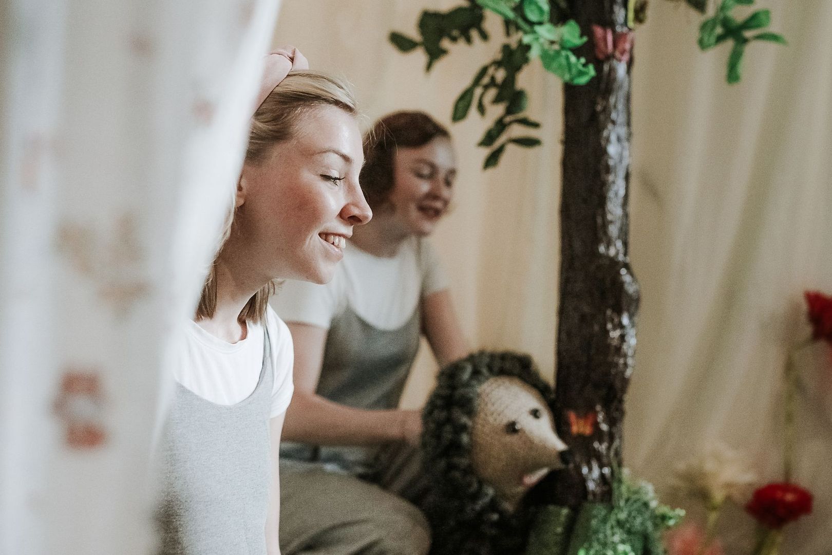 Zwei Frauen gestalten eine märchenhafte Szene mit einer Igel-Handpuppe